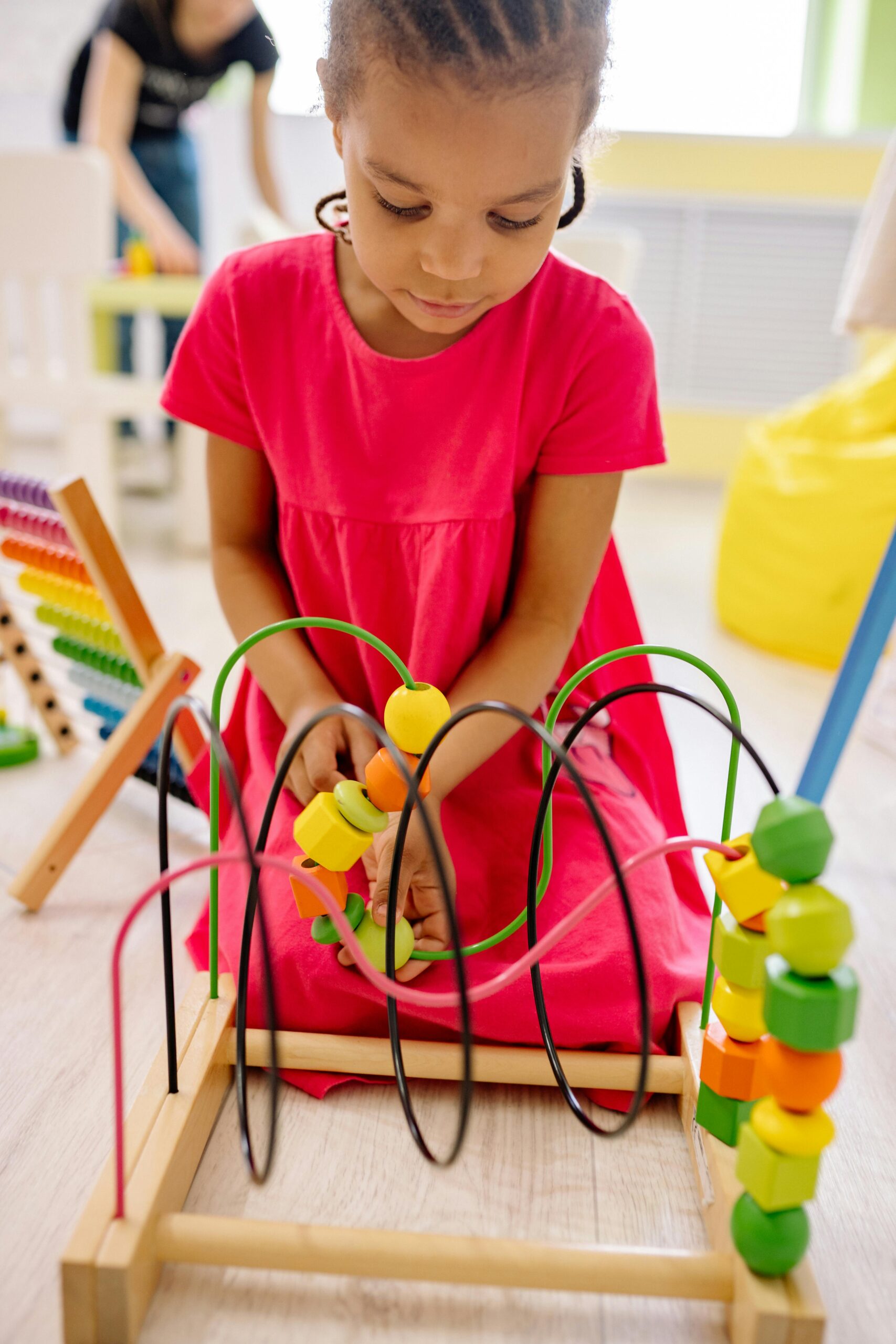 A young girl engages with colorful educational toys in a vibrant classroom setting.